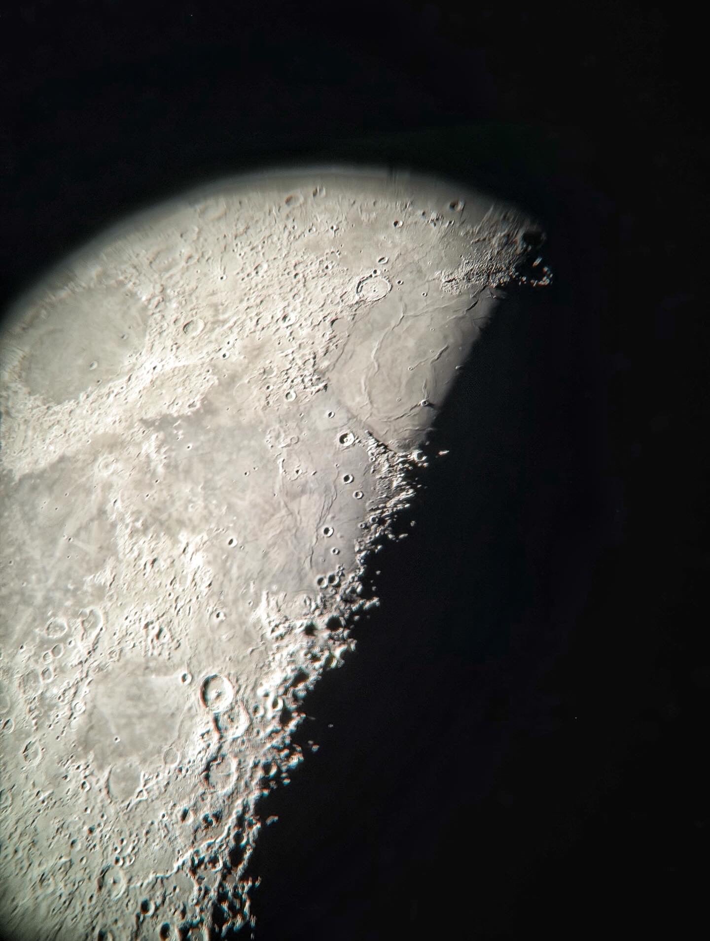 Partial view of the Moon's surface through a telescope with craters and terrain