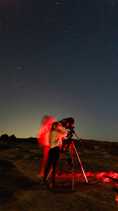 Person using a telescope under a starry night sky